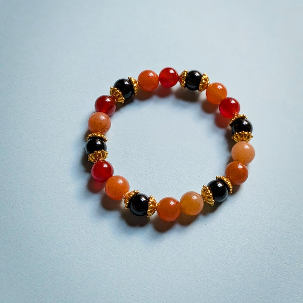 UniquelyYou stretch bracelet featuring red, orange, and black gemstone beads with gold-tone metal spacers.