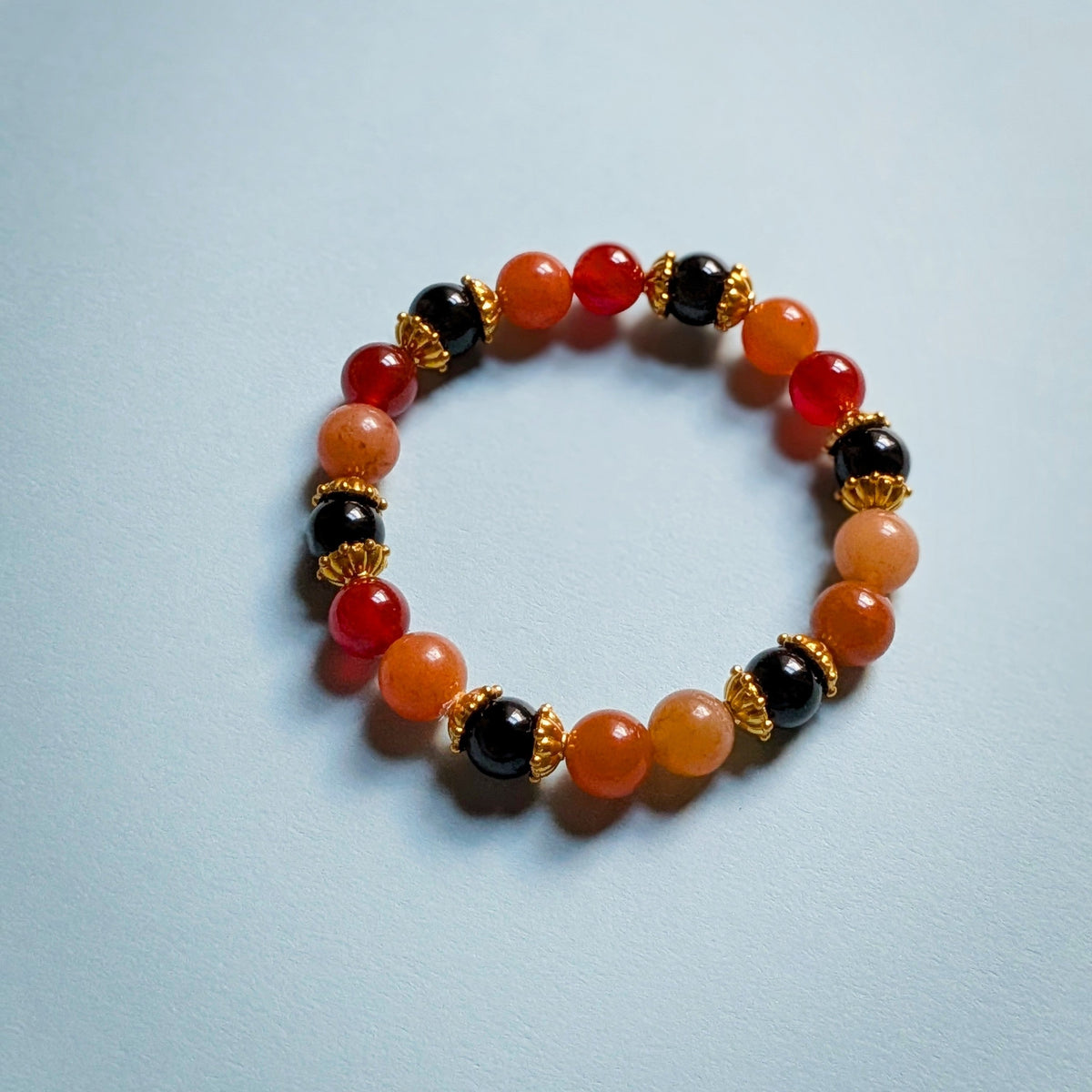 UniquelyYou stretch bracelet featuring red, orange, and black gemstone beads with gold-tone metal spacers.