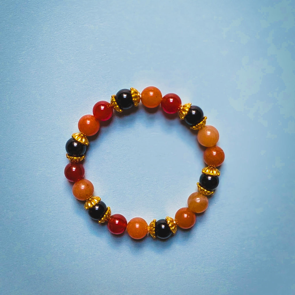 UniquelyYou stretch bracelet featuring red, orange, and black gemstone beads with intricate gold-tone metal spacers.