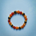 UniquelyYou stretch bracelet featuring red, orange, and black gemstone beads with intricate gold-tone metal spacers.