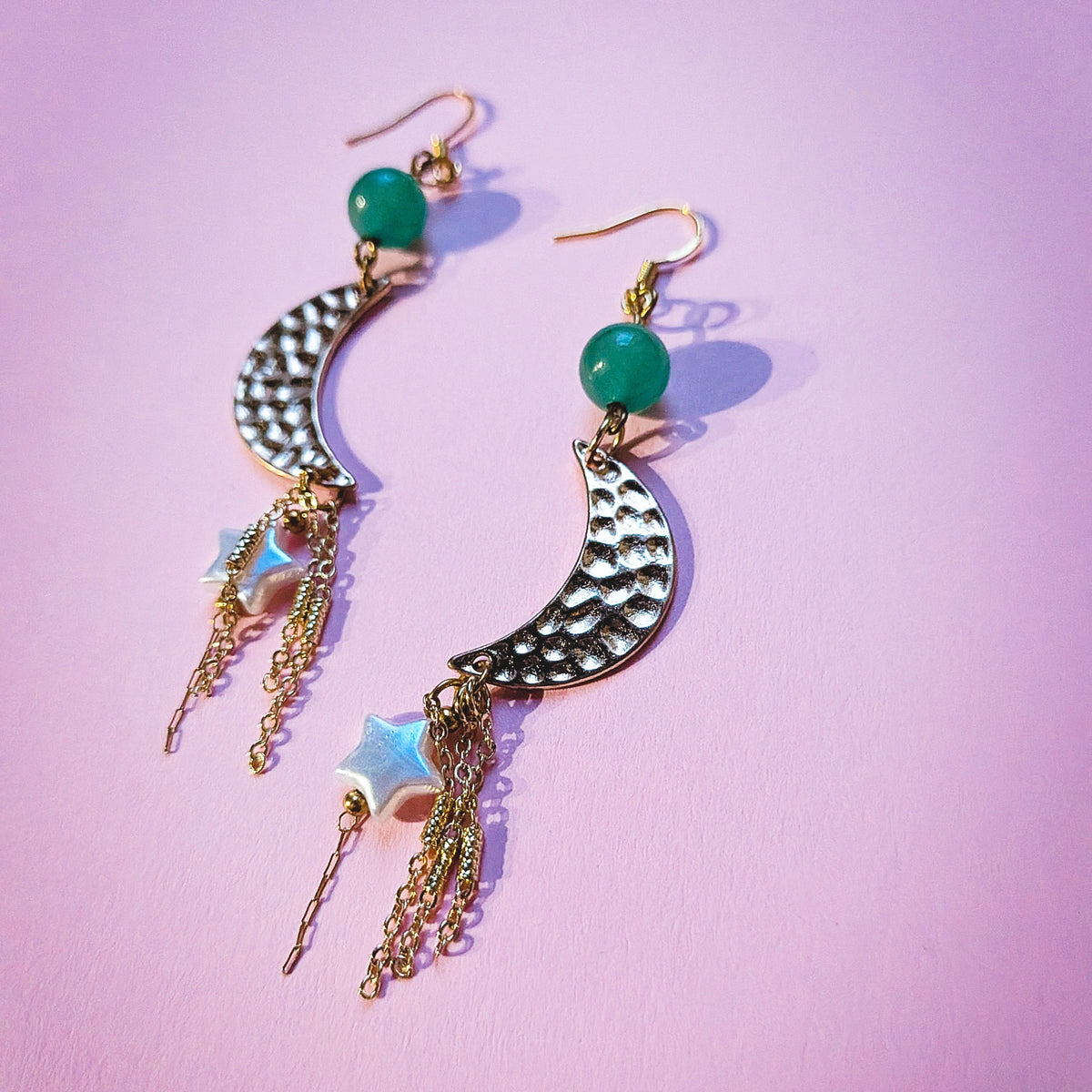 UniquelyYou gold-tone celestial drop earrings featuring textured crescent moons, green beads, stars, and chain tassels.
