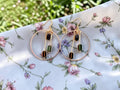 UniquelyYou gold-tone hoop earrings with dangling geometric beads in black, green, and amber. Bohemian style.