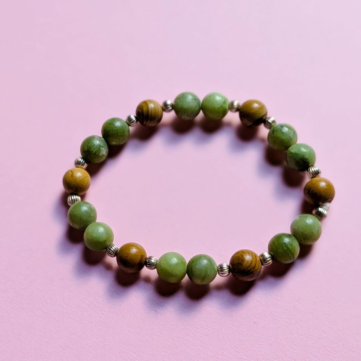 UniquelyYou stretch bracelet featuring green stone and brown wooden beads with silver-tone spacers on a pink background