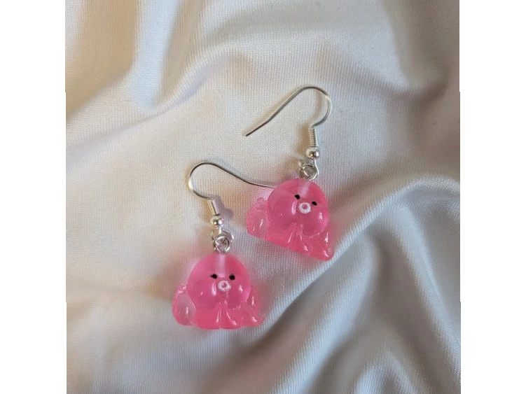 UniquelyYou pink translucent resin flower earrings with black eyes and white centers, dangling from silver hooks.